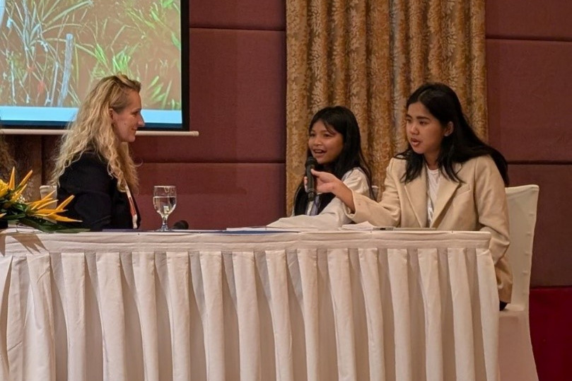 Alma Taslidžan sitzt mit Srey Nang und einem weiteren Mädchen an einem Tisch.