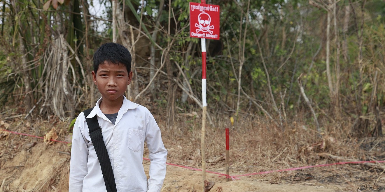 Ein Schuljunge steht vor einem Danger Mines Schild.