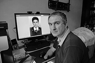 Branislav Kapetanović sitzt vor einem Computer worauf ein Bild aus seiner Militärzeit geöffnet ist.