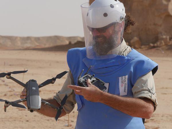 Ein Mann in Entminermonitur hält eine Drohne in den Händen